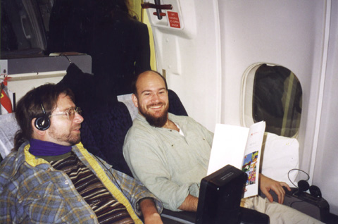 Gene in first class seating on a plane with a friend. There is a lot of room in first class