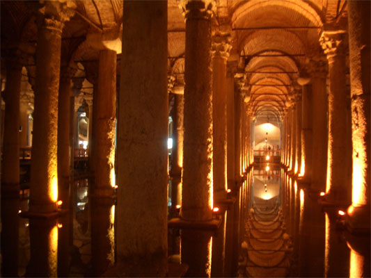 A tall building lit up at night with Basilica Cistern in the background