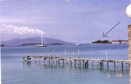 A wooden boat in a body of water with a distant large Buddha in the background