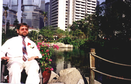 Gene sitting near a pond in Hong Kong while wearing a suit