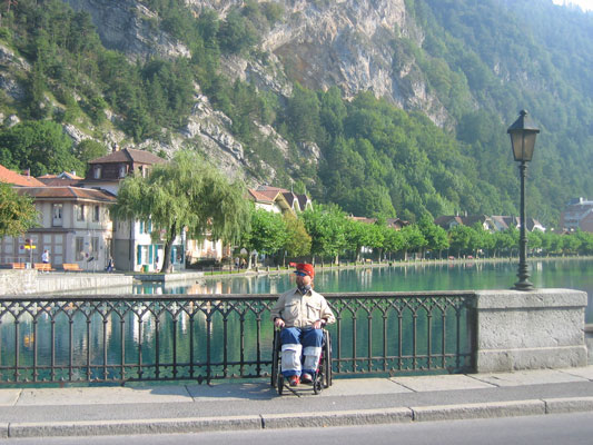 Gene relaxing on a bridge above a river in his wheel chair in Switzerland