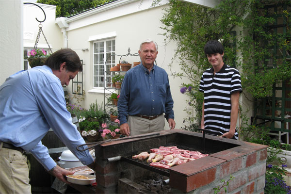 A group of people preparing food, Bobotie, outdoors in a BBQ