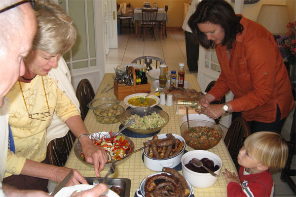 Family gathered around a table filling their plate with BBQ