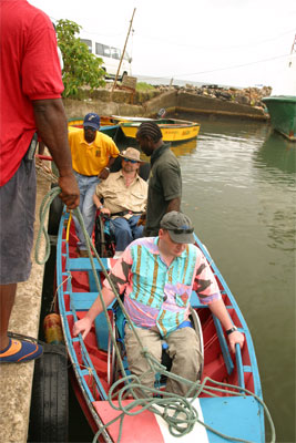 People arriving to a dock within a small boat. Gene is in the back of the boat.