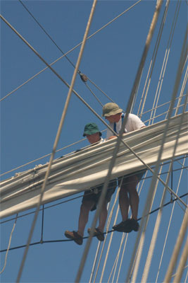 The crew members on the mast of the sail boat.