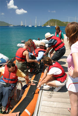 People climbing out of a rubber dingy onto a dock. Gene is helped out of the dingy by crew mates.