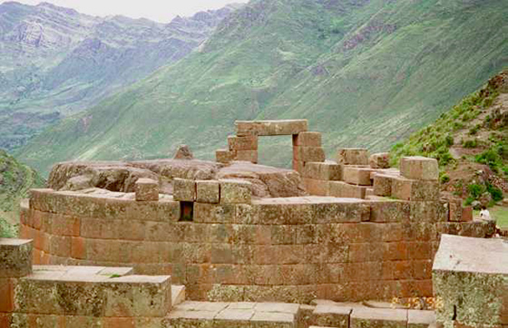 Incan stone ruins with large tall mountains in the distance. 