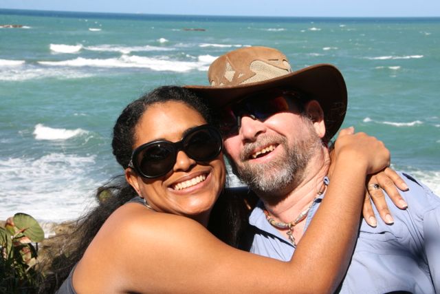 Gene and Dilka smiling for the camera in front of a beach.