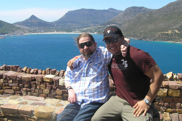 Gene and a friend smiling on a rock wall