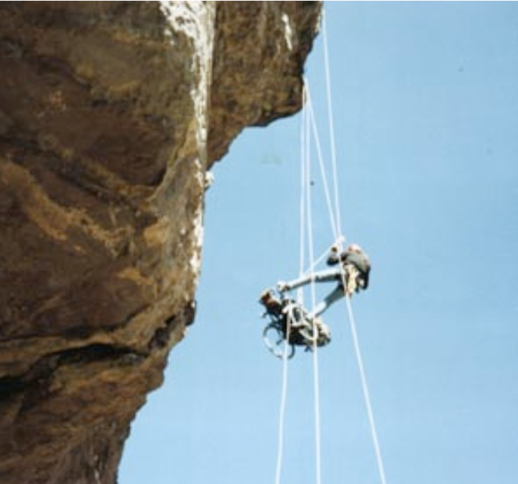 A view of Gene ascending a cliff face from below