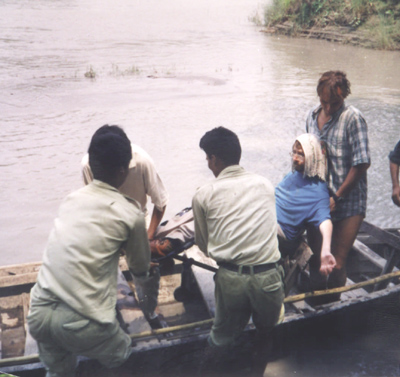 A group of people helping Gene unto a boat in the water