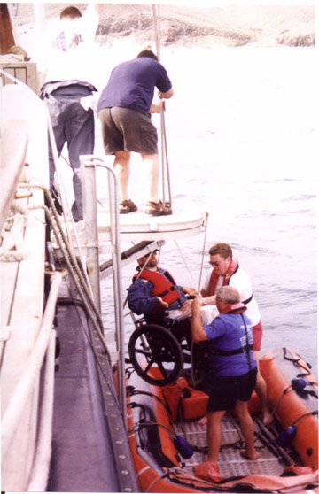 Gene being lowered in his wheelchair into a dinghy