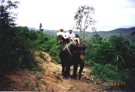 Gene rides an elephant in Thailand with a guide