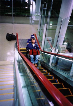 A man Gene going up the escalator in a wheelchair