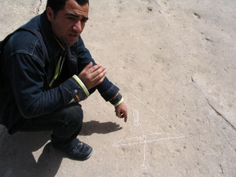Tour guide pointing to a diagram etched out in the sand floor