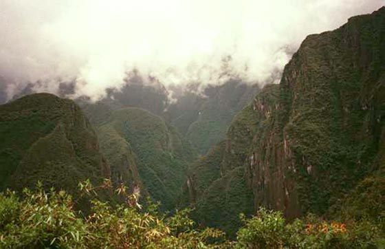 Mountains in Peru, whisps of clouds graze the tops of the tall mountains in the distance.