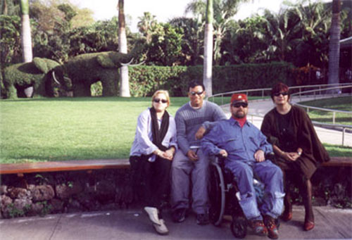 Gene posing with 3 other people in front of a garden