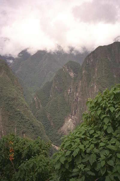 Clouds graze the tops of tall steep mountains in Machu Picchu.