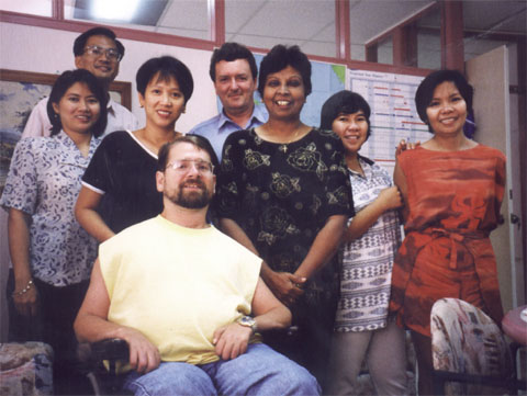 Gene smiles with office personnel in a Philipino office