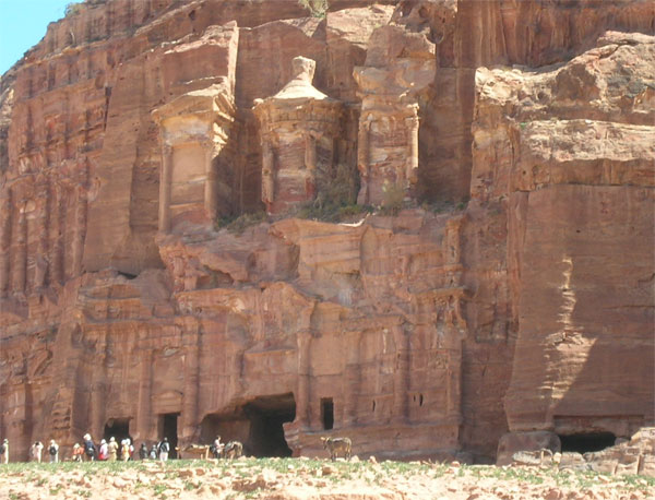 stone building in Petra with people seen walking in the distance 