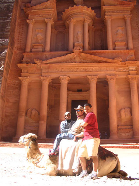 Gene and a guide sitting on top of a camel in front of Petra
