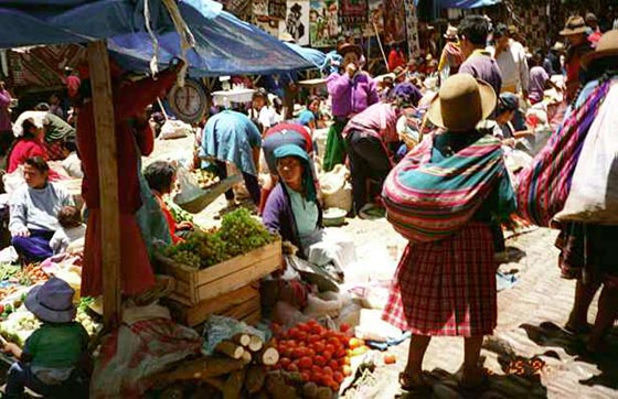A group of people at a an outdoor market selling delicious fresh fruits and vegetables in Peru