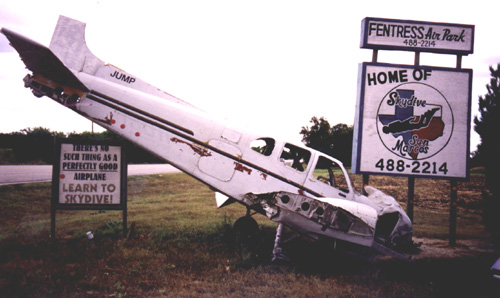 A small plane sitting on top of a sign