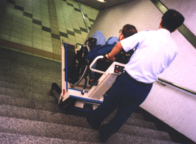 A man assisting a wheelchair user down the stairs