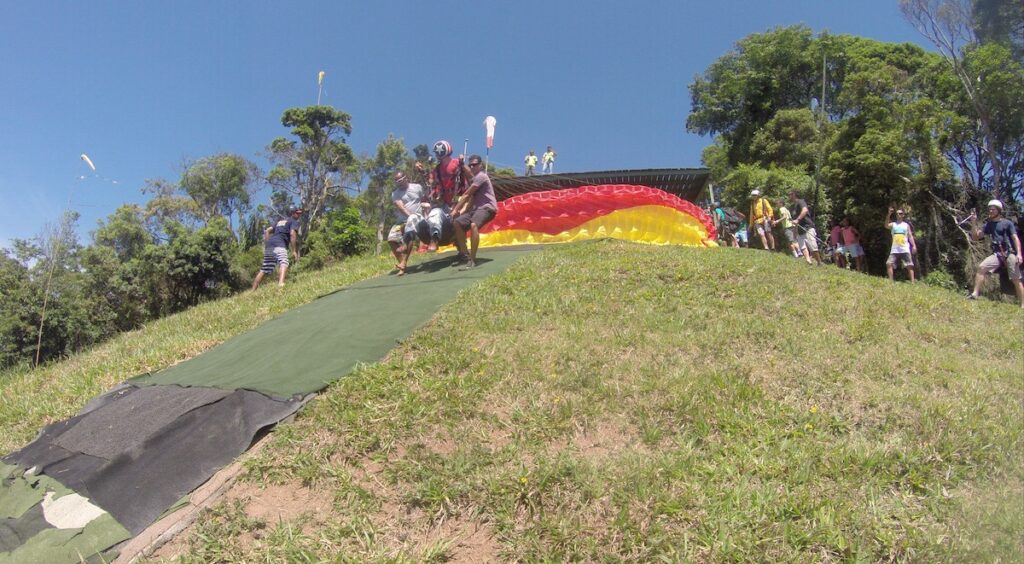 A group of people standing on top of a grass covered field holding Gene getting ready for take-off