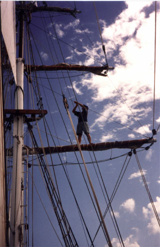 Crew member standing on a year, tending the rigging