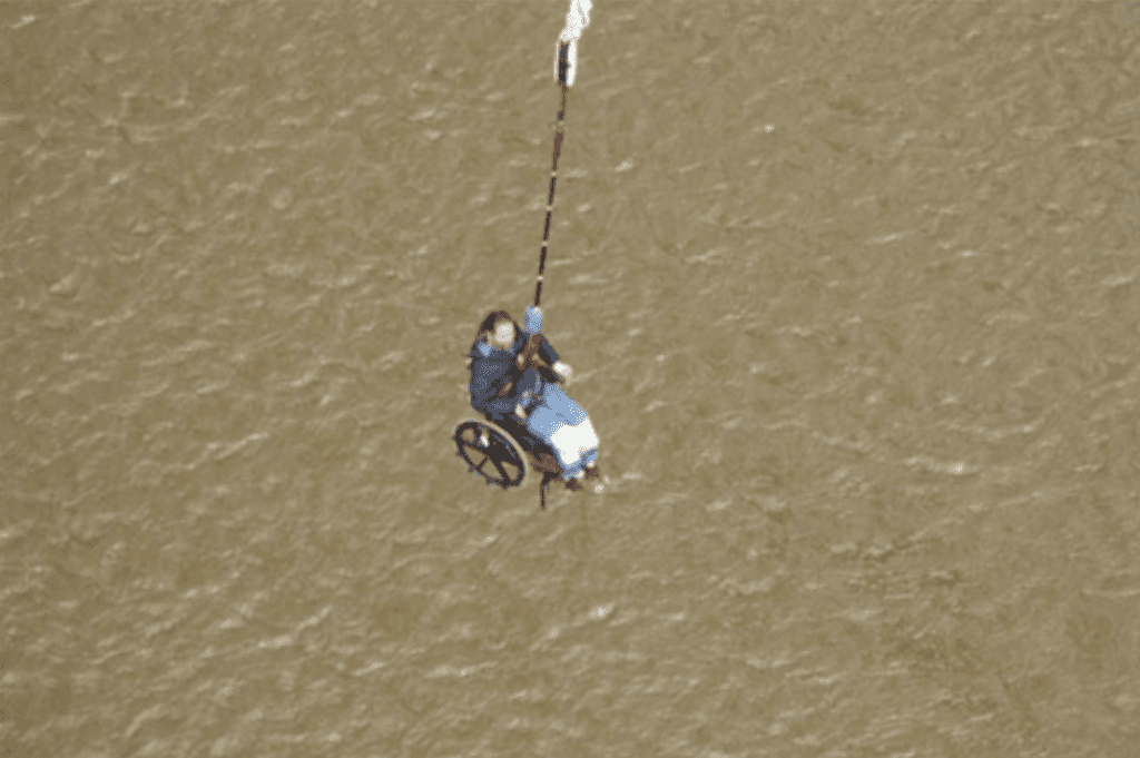 Gene Bridge Swinging, an arial view of him over a body of water while in his wheel chair attached to a rope