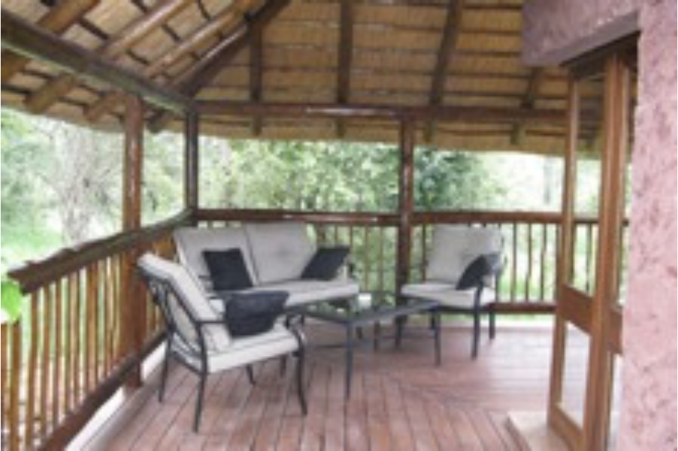 A outdoor deck filled with furniture with lush trees in the background.