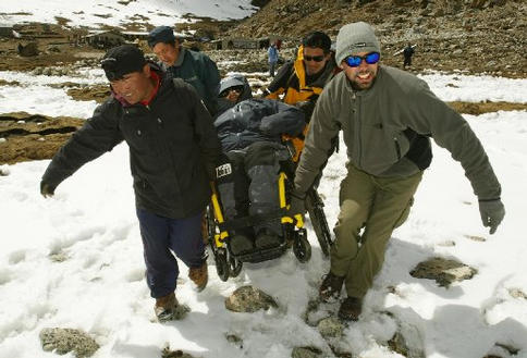 A group of men carrying Gene away from camp.