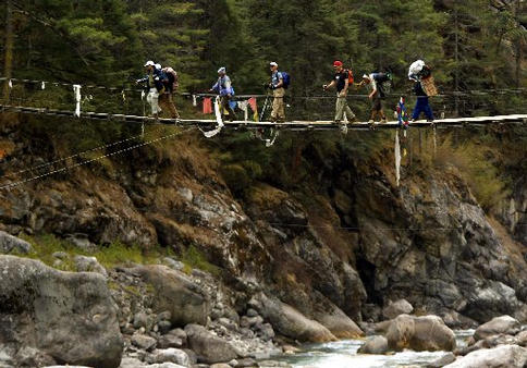 Gene's group walking across a thin bridge seen from a far distance.