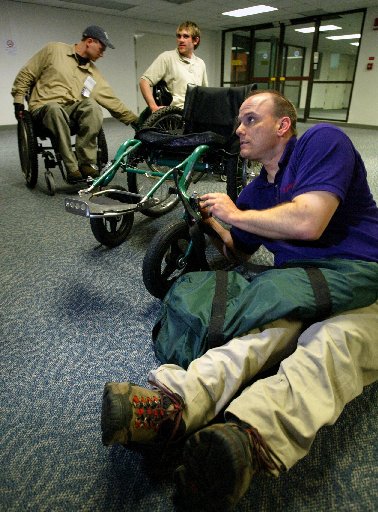 Gene and others at an airport in Nepal on their way to Everest. A man is seen adjusting the wheels on his wheel chair.