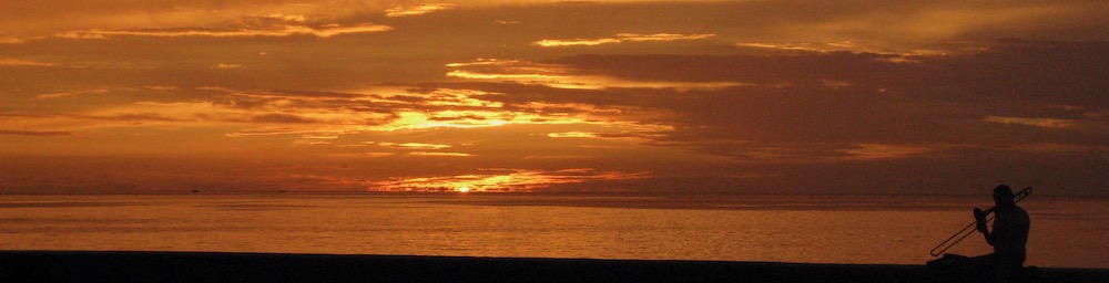 Sunset in the background a silhouette of a trombone player in cuba.