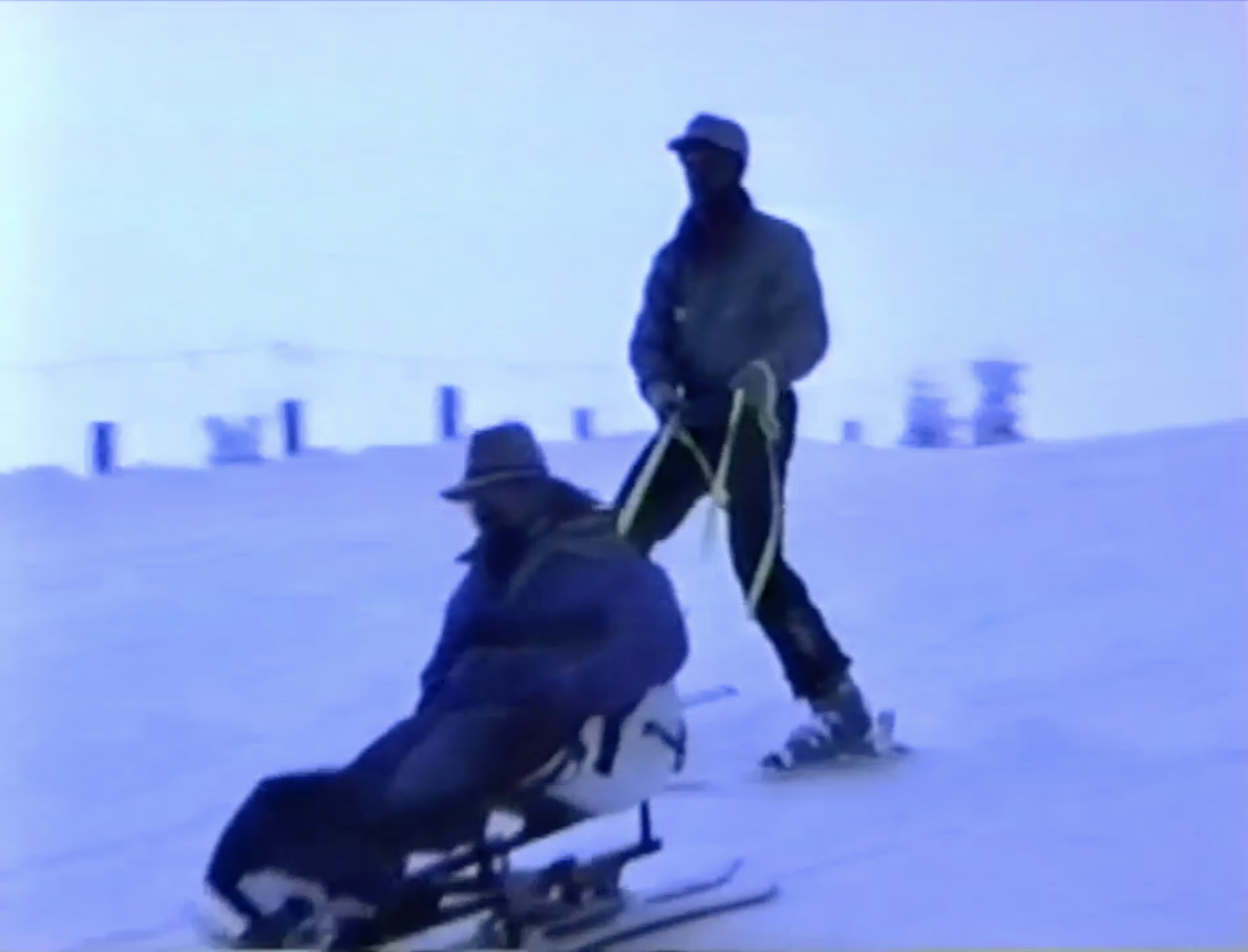 Gene being pushed in the snow on adaptive ski gear