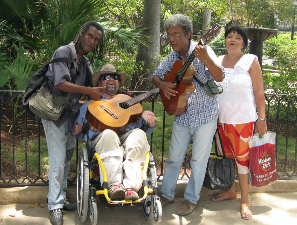 Gene smiling while holding a guitar with a group of musicians.