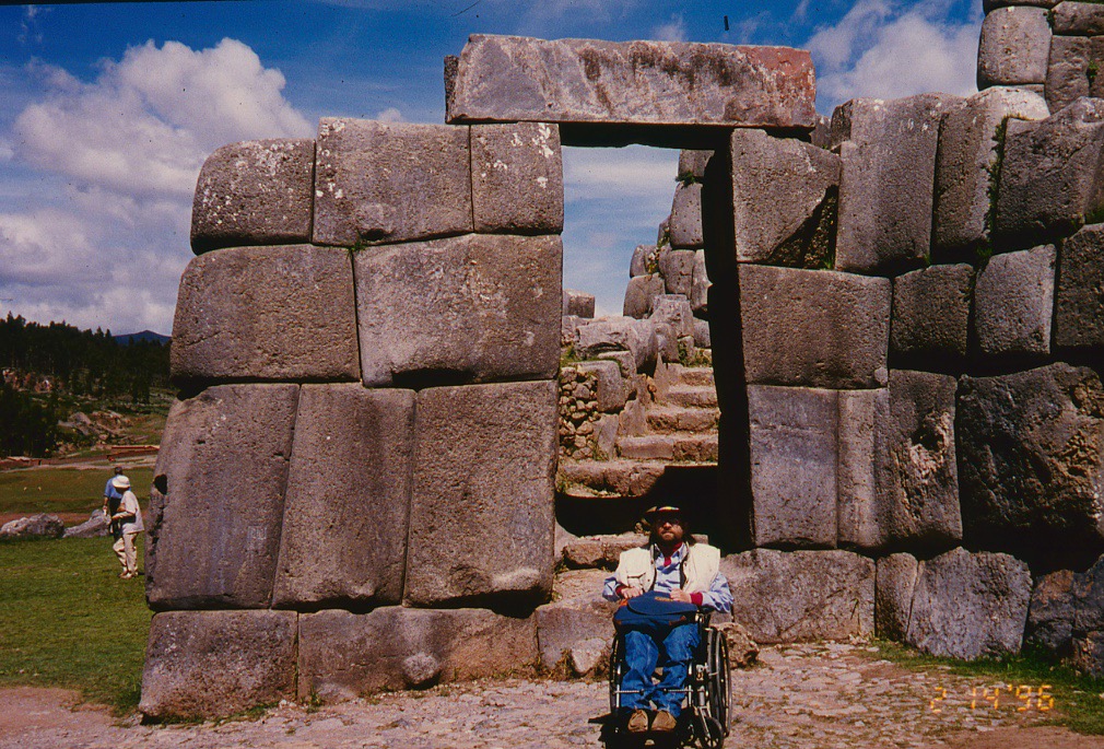 Gene sits in front of stone wall built by the Inca. The stones are large and perfectly fit together without any cement or mortar.