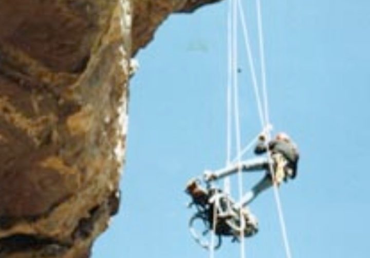 Gene ascending a cliff face with an assistant.