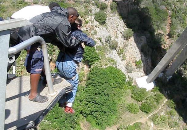 Gene perched on edge of a 210 foot high bridge, attached to a bungee cord, about to be pushed off.