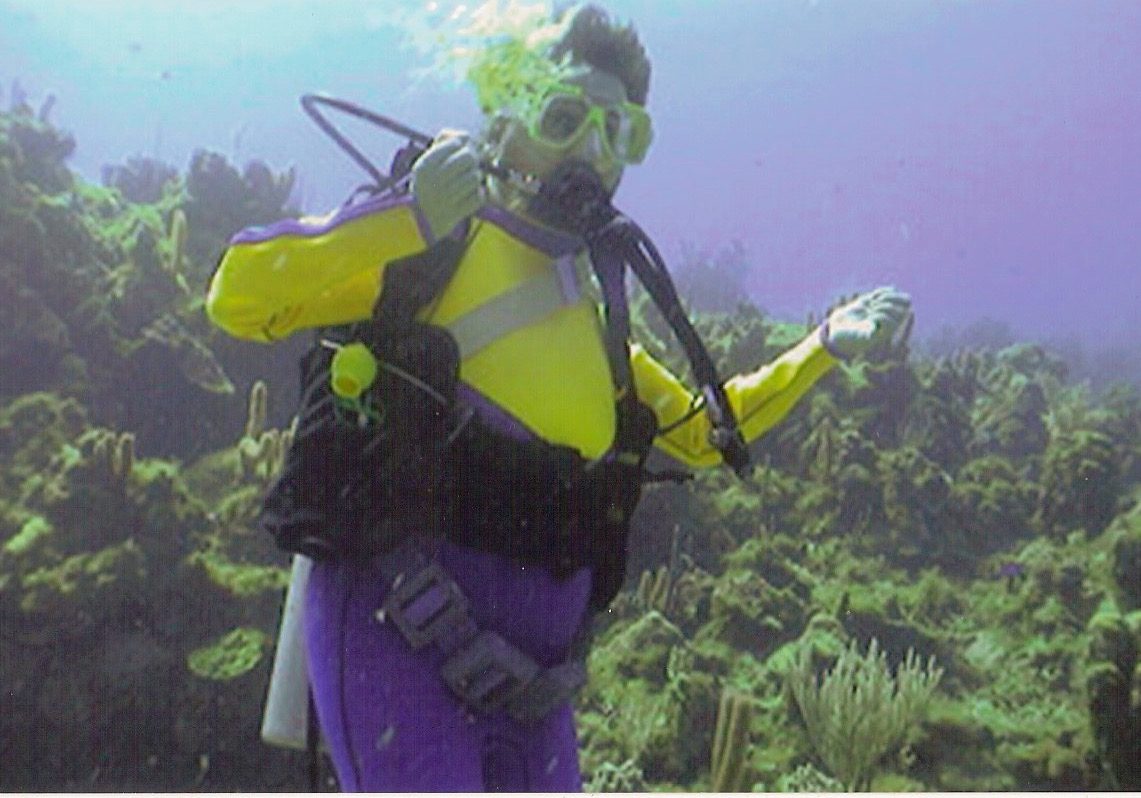 Gene floats upright in front of coral